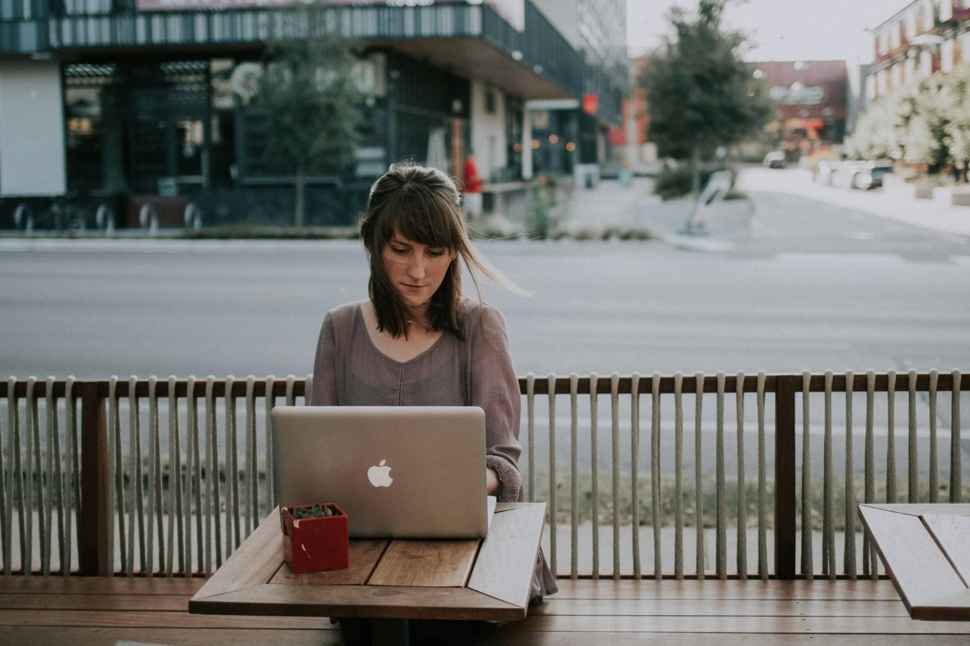 Een foto van een vrouw die op haar laptop buiten een kwartaalplanning aan het maken is.